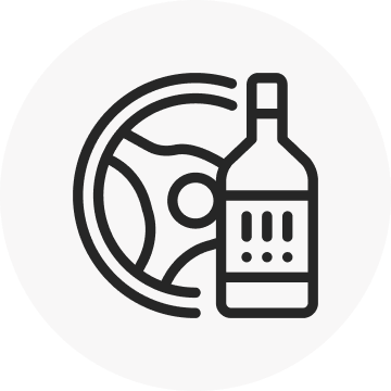 A black and white line art icon showing a bottle of alcohol in front of a steering wheel, symbolizing driving under the influence (DUI) or drunk driving.