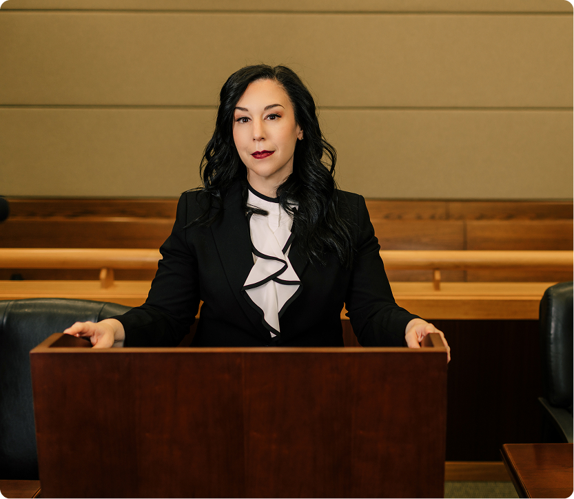 Estate Planning Attorney in Connecticut Courtroom Professional female estate planning attorney in black suit with white ruffled blouse standing confidently at courtroom podium